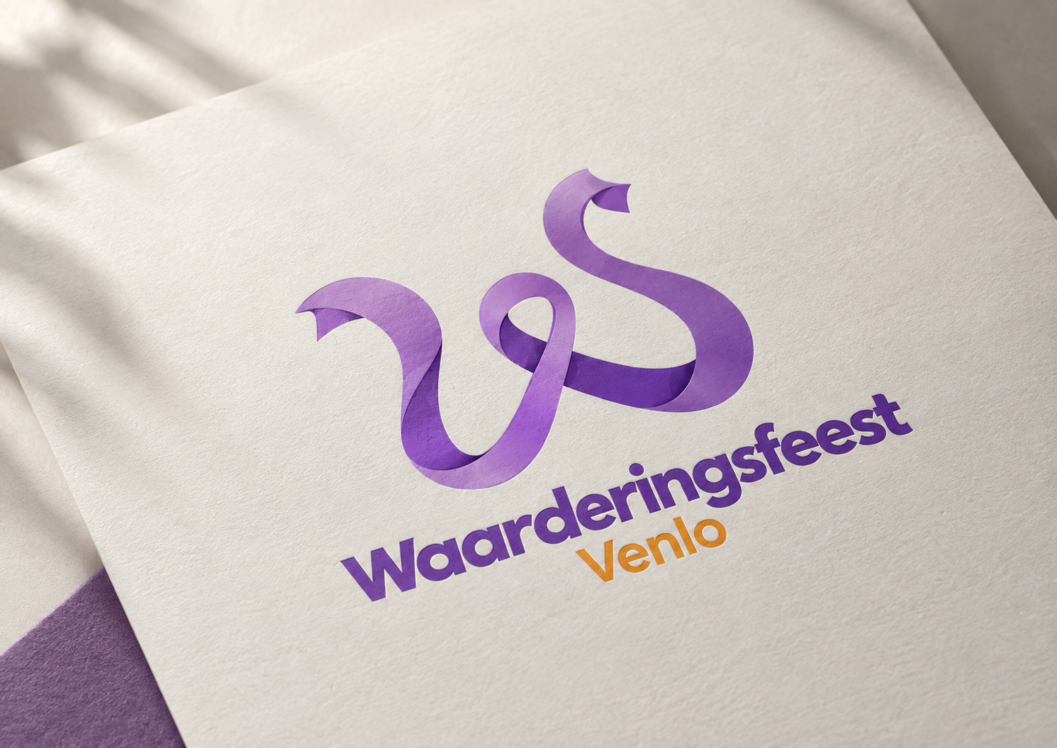 Het logo van Waarderingsfeest Venlo met het paarse lint, gedrukt op een textuurrijke licht crèmekleurige kaart