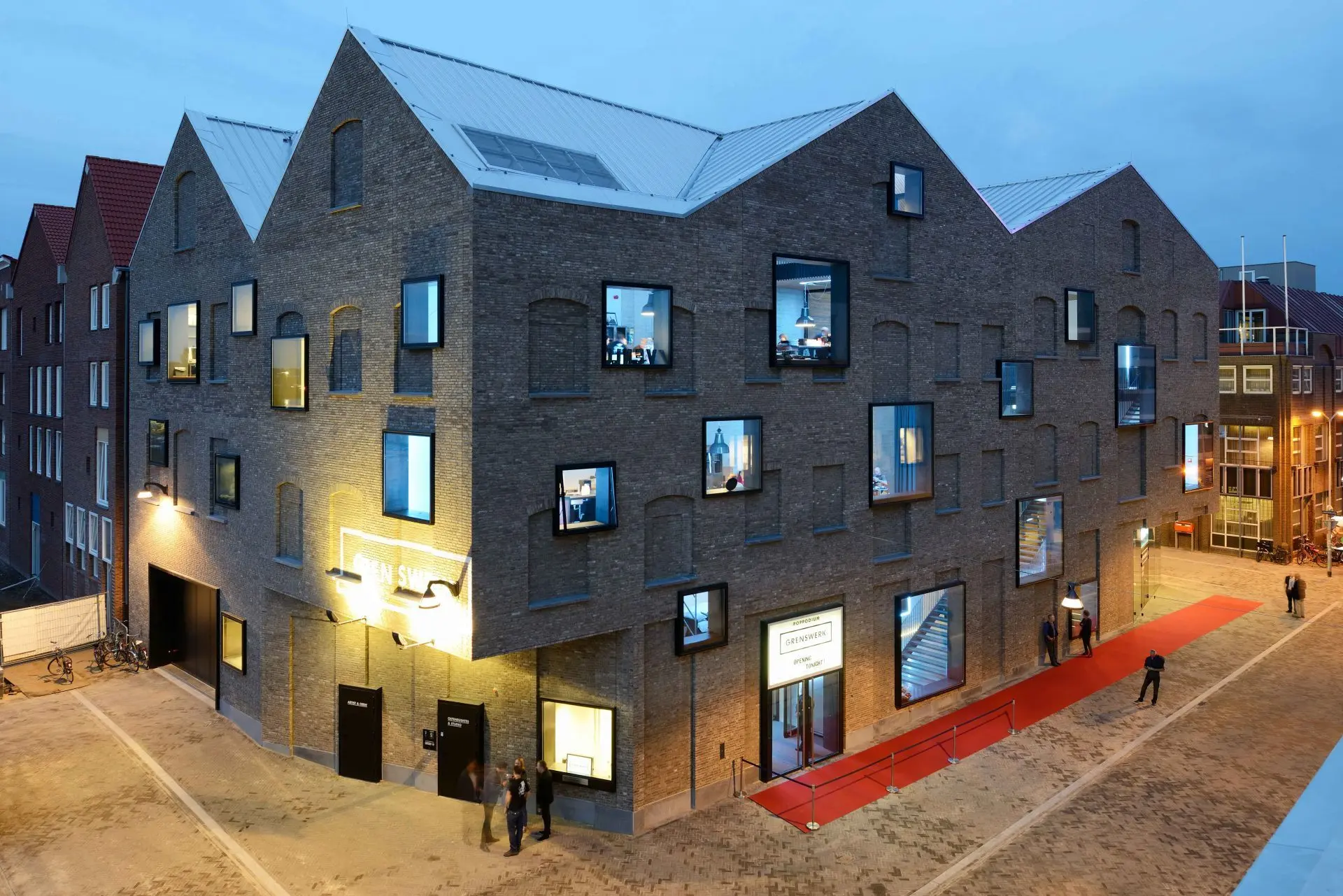 Poppodium Grenswerk in Venlo-Centrum bij avond, met verlichte gevel, het bord POPPODIUM GRENSWERK en een rode loper voor de ingang
